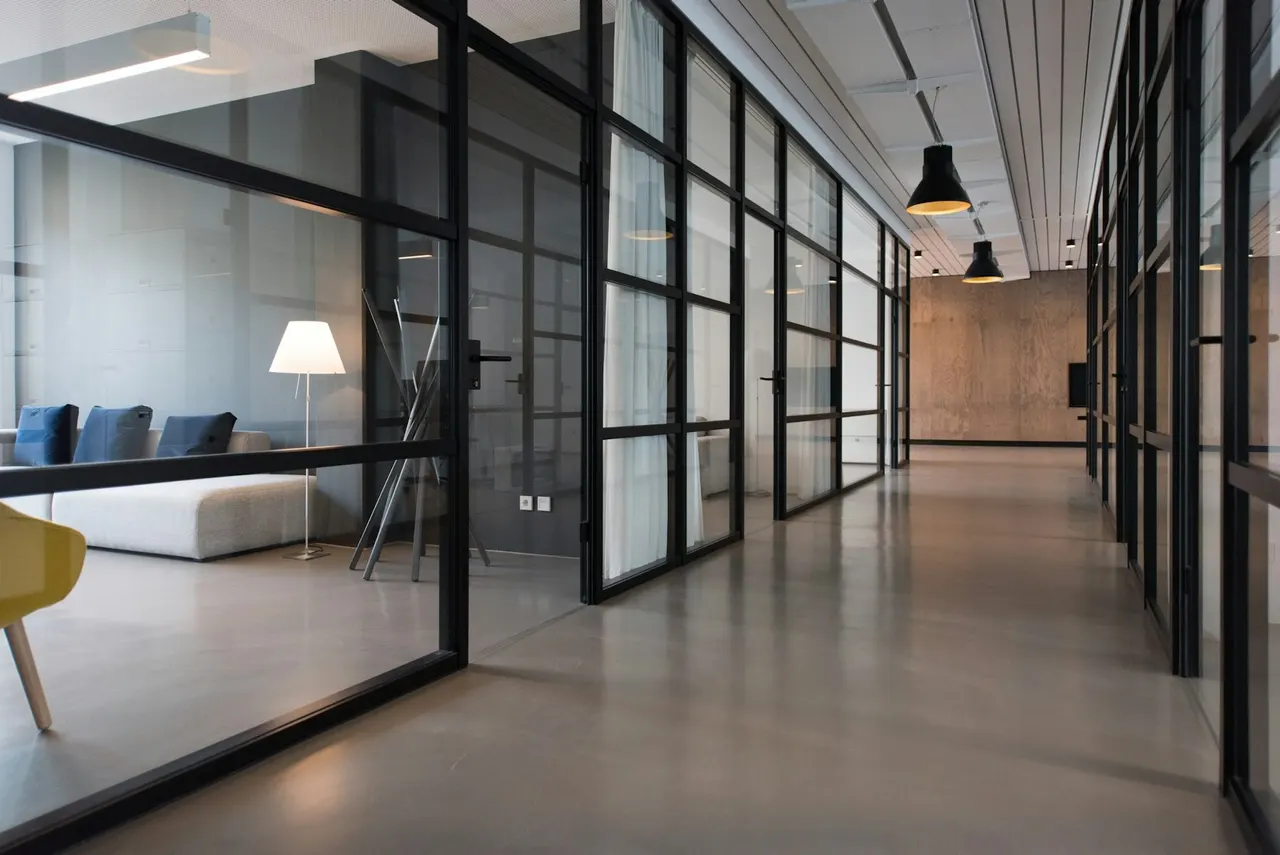A quiet modern office corridor with glass-walled meeting rooms